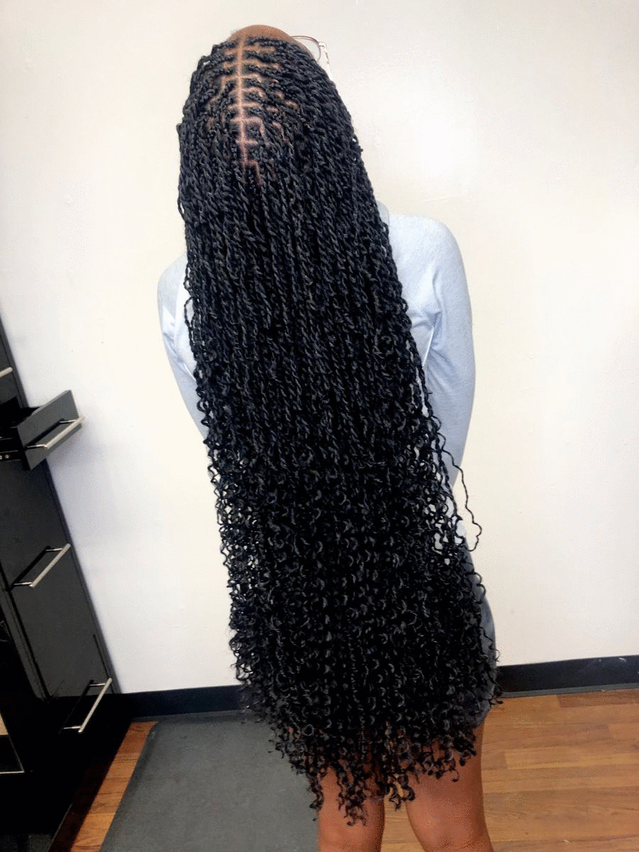 Client with long knotless braids in a warm, modern braiding salon
