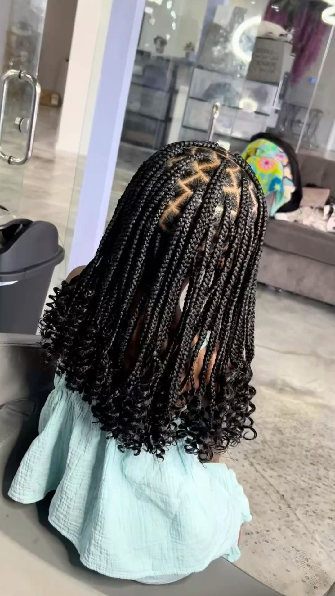 Child wearing neat braids with curled ends in the salon